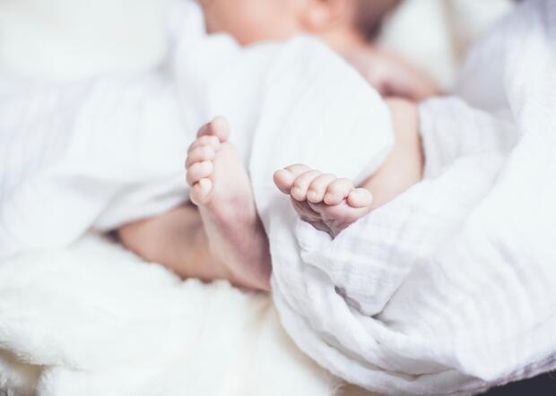 Auf dem Rücken liegen und sich frei bewegen: Babyfüße in weißem Bettlaken